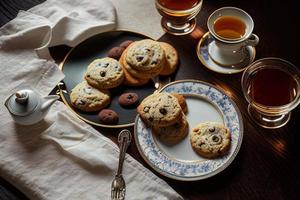 photography of a plate of cookies and a glass of tea on a table with a cloth and a napkin on it photo