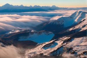 aerial landscape photo shot of a mountain from above, mist and snow
