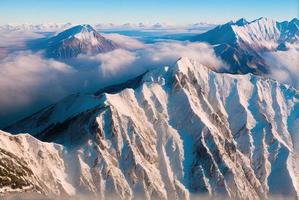 aerial landscape photo shot of a mountain from above, mist and snow