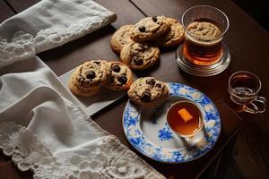 photography of a plate of cookies and a glass of tea on a table with a cloth and a napkin on it photo