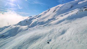 as pessoas esquiam na estância de esqui nas montanhas durante o inverno. atividades e esportes de inverno. estilo de vida aventureiro. casa da montanha ao fundo. video