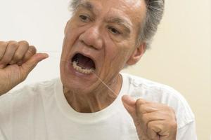 Senior man flossing his teeth with dental floss photo