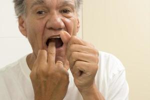 Senior man flossing his teeth with dental floss photo