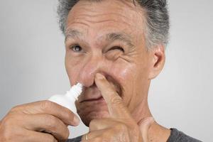 Senior man using a Nasal Spray for his dry nose photo