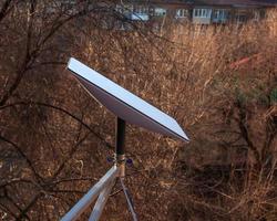 Starlink satellite dish, an internet constellation operated by SpaceX, is installed on the wall of an apartment building. View from the window of the apartment. photo