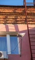 Starlink satellite dish, an internet constellation operated by SpaceX, is installed on the wall of an apartment building. photo