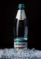 KRASNOYARSK, RUSSIA - OCTOBER 21, 2022 A bottle of Borjomi mineral water stands on a hill of crushed ice.