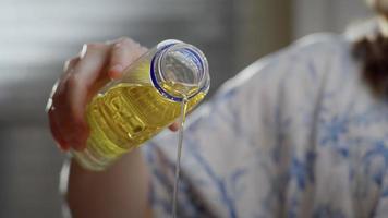 femme verse de l'huile d'une bouteille