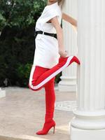 modelo con un vestido blanco y botas altas de cuero rojo está tomando una foto