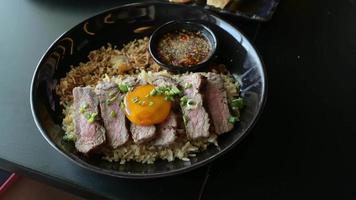 Rinderfett Knoblauch gebratener Reis mit Rindersteak und Topping mit eingelegtem Eigelb in einer Schüssel. gegrilltes Fleisch, thailändisches Menü ist Fusionsküche.