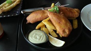 Panning lateral de filmagem em 4k, família e amigos desfrutam de comer peixe e batatas fritas em um café inglês tradicional. batatas fritas com batatas fritas no restaurante de fast food servidas com maionese para mergulhar. video