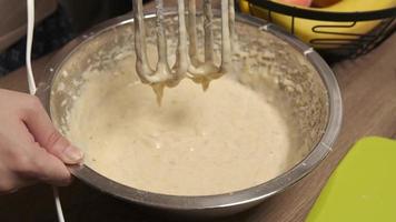 Woman chef mixes dough for banana bread with a whisk, pouring yogurt, close-up. Banana cake dough preparing. Delicious homemade dessert baked, tasty snack for morning breakfast. Homemade banana bread video