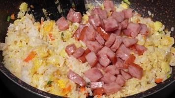 Chef frying rice with corn and bacon in pan close-up. Woman chief cooking dish with grilled vegetables, meat, Ingredients for fried rice recipe . Food and cook concept. video