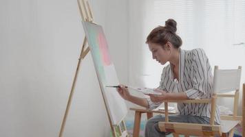 skön kvinna hobbies handla om konstnär och använda sig av paintbrush i abstrakt konst för skapa mästerverk. målare måla med akvareller eller olja i studio hus. njut av målning som hobby, rekreation, inspiration video