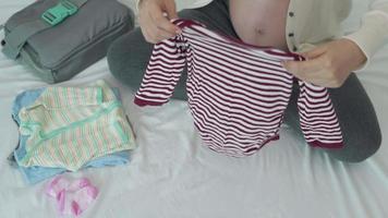 as mulheres grávidas estão dobrando as roupas depois de encomendá-las e limpá-las para se preparar para seus filhos. idéias para preparar acessórios de roupas de bebê para novos pais e mães. video