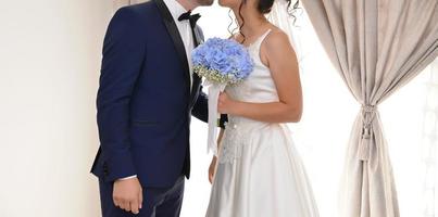 bride and groom together holding a blue flower bouquet photo