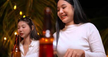 filmagem de amigos asiáticos felizes jantando juntos - jovens sentados na mesa do bar brindando ao jantar com garrafa de cerveja ao ar livre - pessoas, comida, estilo de vida de bebida, conceito de celebração de ano novo. video