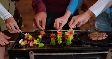 antal fot av vän grupp matlagning kött på utegrill grill på ny år fest. bar-bq eller bbq på traditionell spis. natt fest, människor och firande begrepp. video