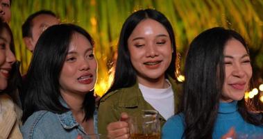 Aufnahmen von glücklichen asiatischen Freunden, die zusammen zu Abend essen und sich selbst feiern - junge Leute, die Biergläser im Freien anstoßen - Menschen, Essen, Trinken, Lifestyle, Neujahrsfeierkonzept.