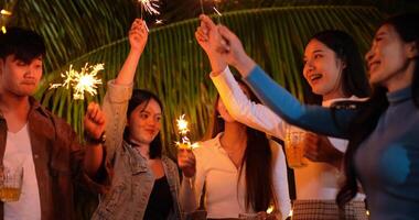 filmagem de grupo asiático feliz de amigos se divertindo com estrelinhas ao ar livre - jovens se divertindo com fogos de artifício durante a noite - pessoas, comida, estilo de vida de bebida, conceito de celebração de ano novo. video