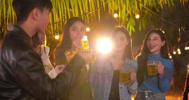 Footage of Happy Asian friends having dinner party together - Young people toasting beer glasses dinner outdoor  - People, food, drink lifestyle, new year celebration concept.