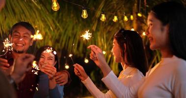 beeldmateriaal van gelukkig Aziatisch groep van vrienden hebben pret met sterretjes buitenshuis - jong mensen hebben pret met vuurwerk Bij nacht tijd - mensen, voedsel, drinken levensstijl, nieuw jaar viering concept. video