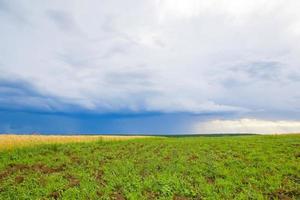 green field landscape with blue sky and stormy clouds. photo