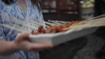 mujer bajando las escaleras con brochetas de pollo video