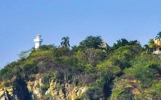 pequeño faro blanco sobre un acantilado en puerto escondido méxico. foto