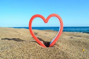 Red plastic heart on the beach photo