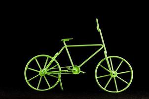 Green toy bike on black background photo