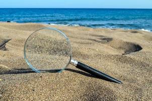 Magnifying glass in the sand photo