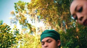 Asian couple walking down the hill above the mountain with a forest in the background while chatting together in green clothes video