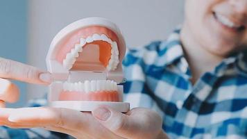 conceito de estomatologia, retrato parcial de menina com fortes dentes brancos, olhando para a câmera e sorrindo, dedos perto do rosto. closeup de jovem no dentista, estúdio, dentro de casa video