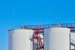 White fuel storage tanks against blue sky background photo