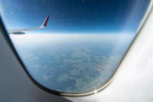 vista de la ventana del avión al cielo nublado y la tierra. hermoso paisaje desde la cabina del avión. volar sin miedo a volar, incidentes y turbulencias. foto