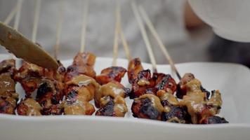 verser la sauce aux cacahuètes sur le satay de poulet video