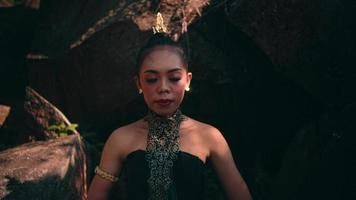 Asian woman in traditional green dress meditating lonely in peacefully in front of the big rock at the mountain video