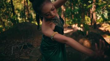 balinese donna fare il danza movimento dentro il foresta mentre indossare un' verde vestito e trucco video