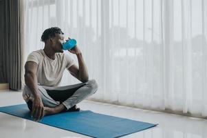 man drinking water after exercise at home photo