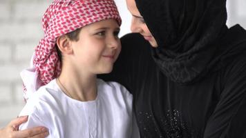 Happy Arabic mother and son together sitting on the couch and reading a book. video