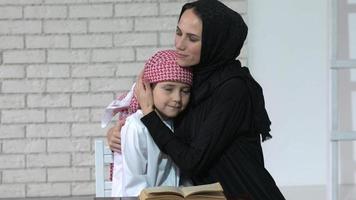 contento Arabo madre e figlio insieme seduta su il divano e lettura un' libro. video