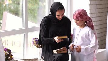 contento Arabo madre e figlio insieme seduta su il divano e lettura un' libro. video