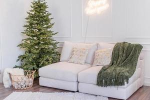 Christmas tree with presents and lights and sofa in light and airy living room photo