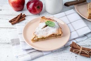 Homemade piece of apple pie with fresh red apples on white table photo