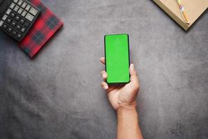 Vista superior de la mano del hombre con un teléfono inteligente en el escritorio de la oficina foto