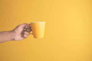 close up of man hand holding yellow color mug photo