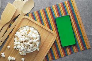 top view of smart phone and popcorn on table photo