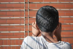 sad teenage boy looking through window photo