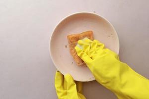 sponge , rubber gloves and colorful plate on blue photo